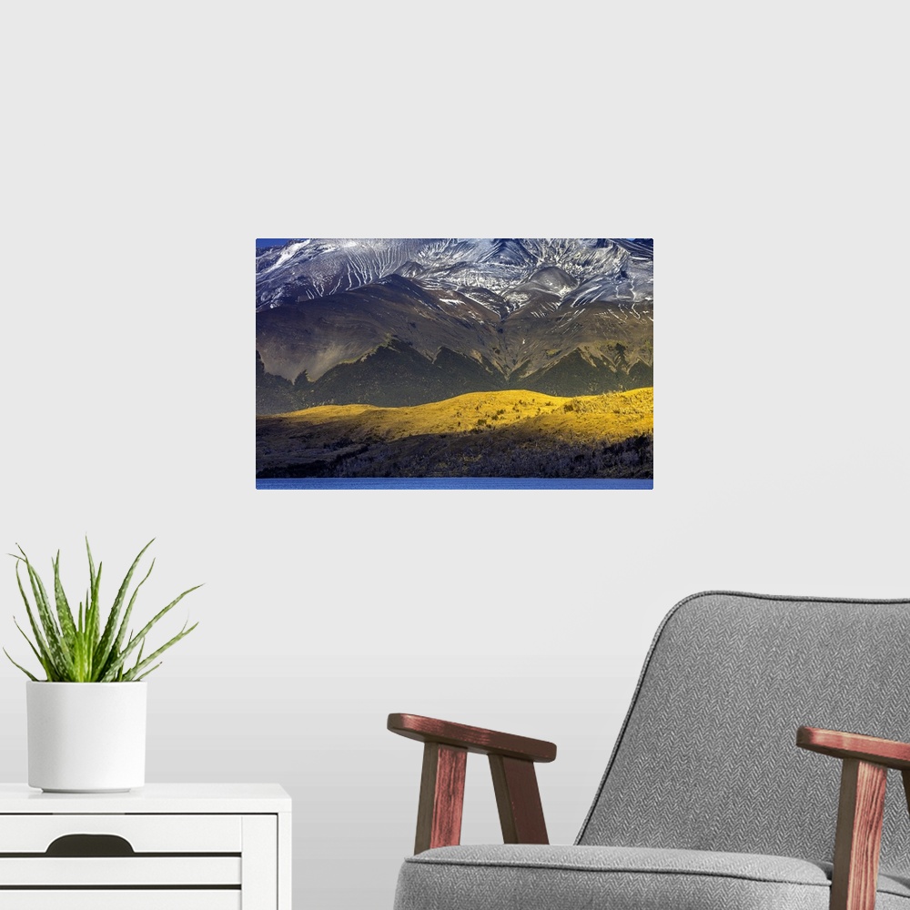 A modern room featuring Sunlight on the side of the mountains under the snowy peaks of the Andes in Chile.