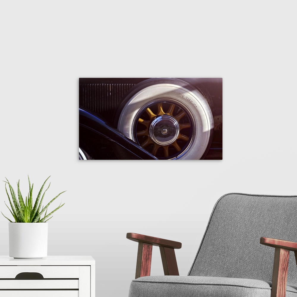 A modern room featuring Close Up View of a Woddeen Spoked Spare Wheel with Whitewall Tires of an Antique Automobile