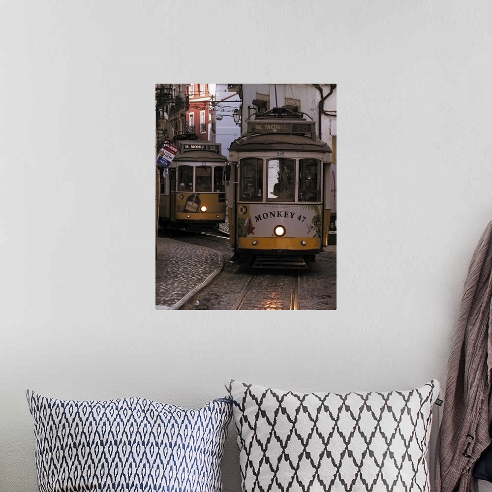 A bohemian room featuring Vintage trams of line 28 traveling in a narrow street in Alfama district of Lisbon at dusk, Portu...