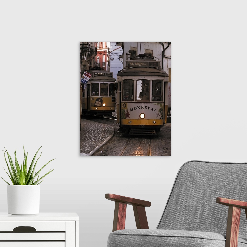 A modern room featuring Vintage trams of line 28 traveling in a narrow street in Alfama district of Lisbon at dusk, Portu...