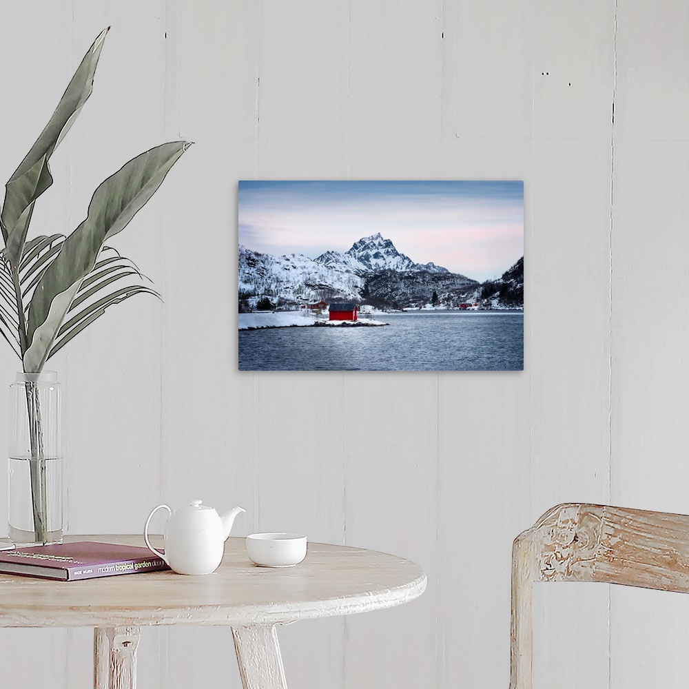 A farmhouse room featuring A photograph of a red building sitting on the shoreline of a snowy landscape with mountains in th...