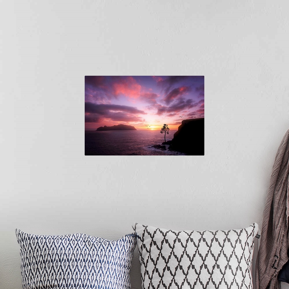 A bohemian room featuring Rocky cliffs on the ocean under a cloudy sky lit up with sunset light.