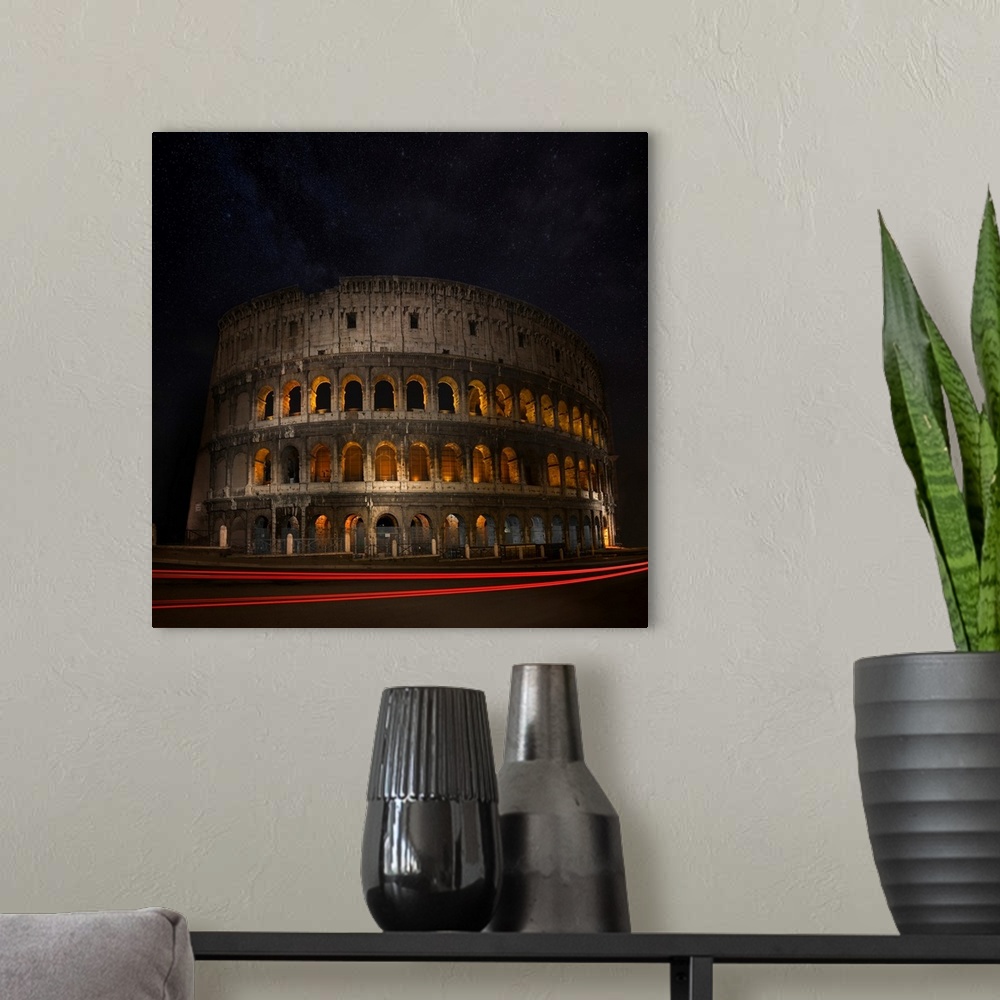 A modern room featuring The Colosseum in Rome illuminated at night with light trails from passing cars.