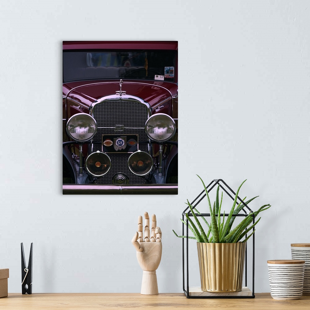 A bohemian room featuring The front grille and round headlights of a maroon colored vintage car.