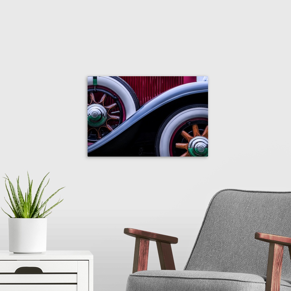 A modern room featuring Front and spare wheels on the side of a vintage car.