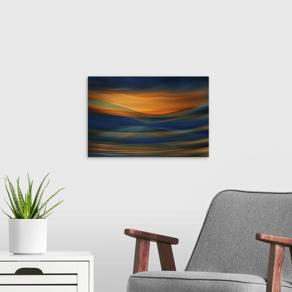 A modern room featuring Abstract photograph of blurred and blended colors and flowing lines in shades of orange and blue.