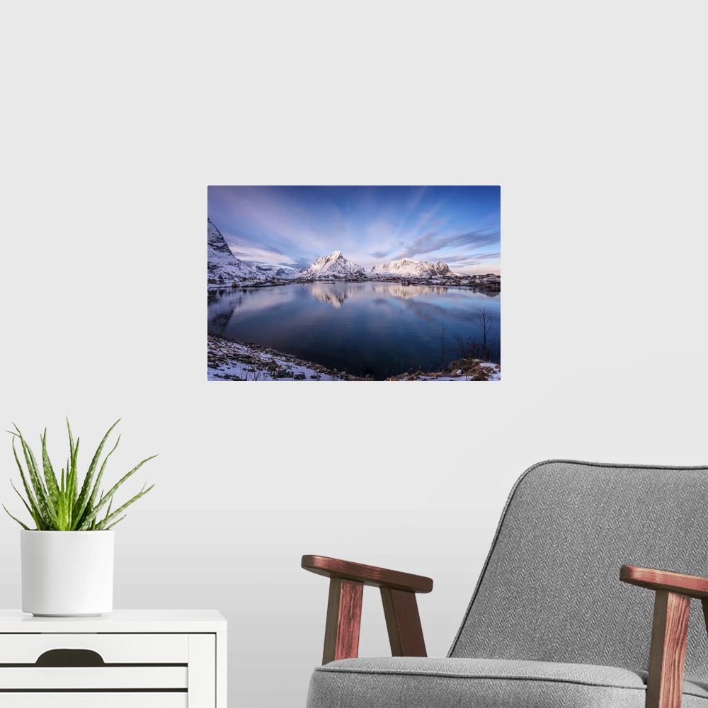 A modern room featuring A photograph of snow covered mountains seen from the shore of a lake.