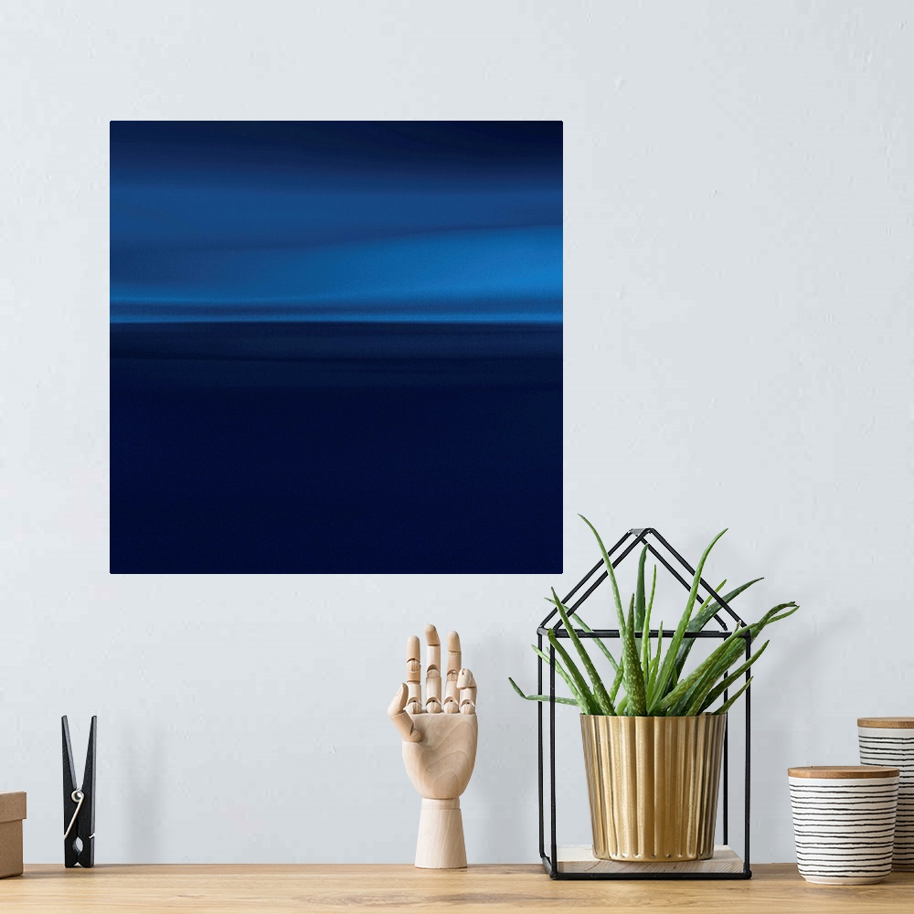 A bohemian room featuring Abstract artwork that has lighter shades of blue at the top of the print that becomes darker as y...