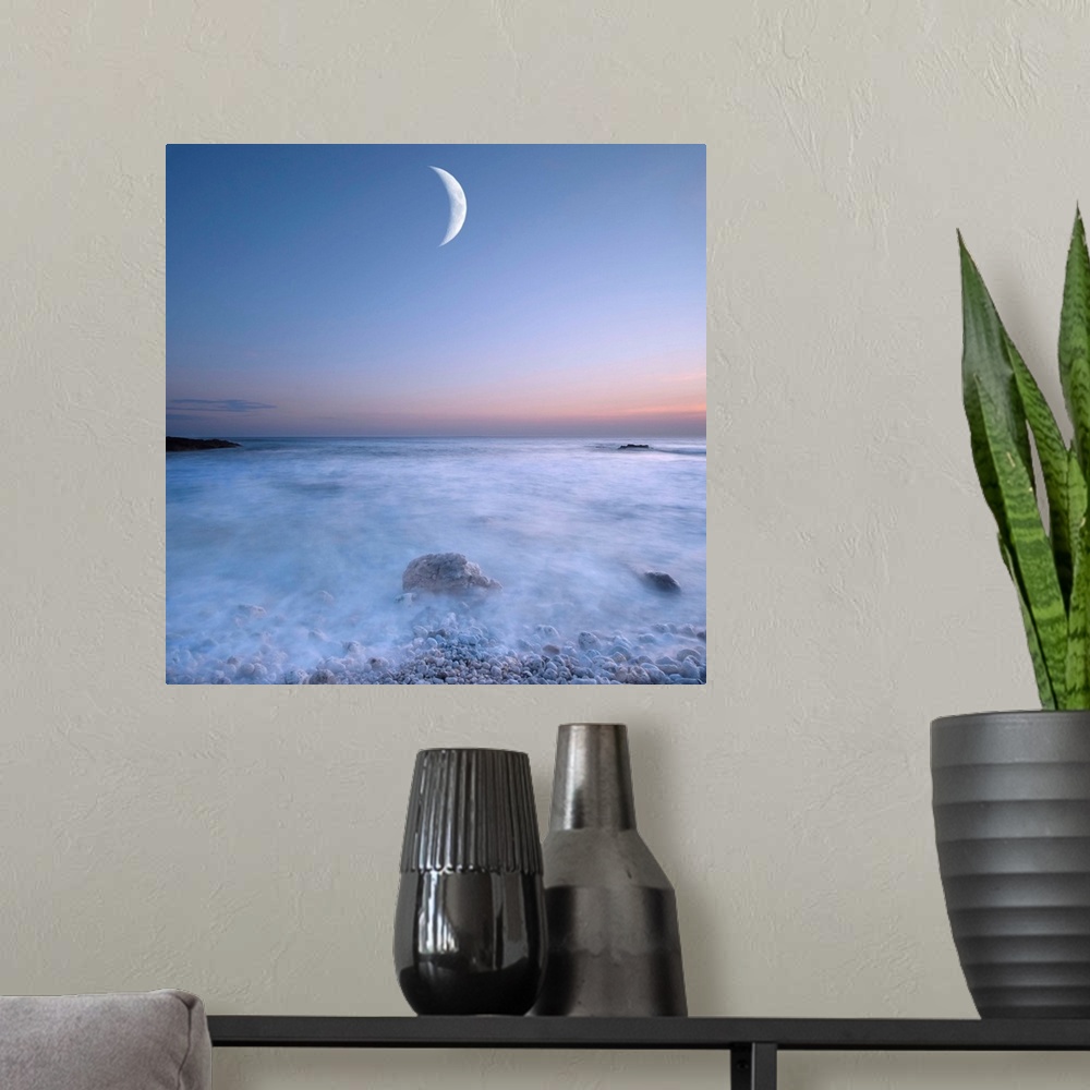 A modern room featuring This large art piece highlights a crescent moon with fog cascading over the rocks and water below.