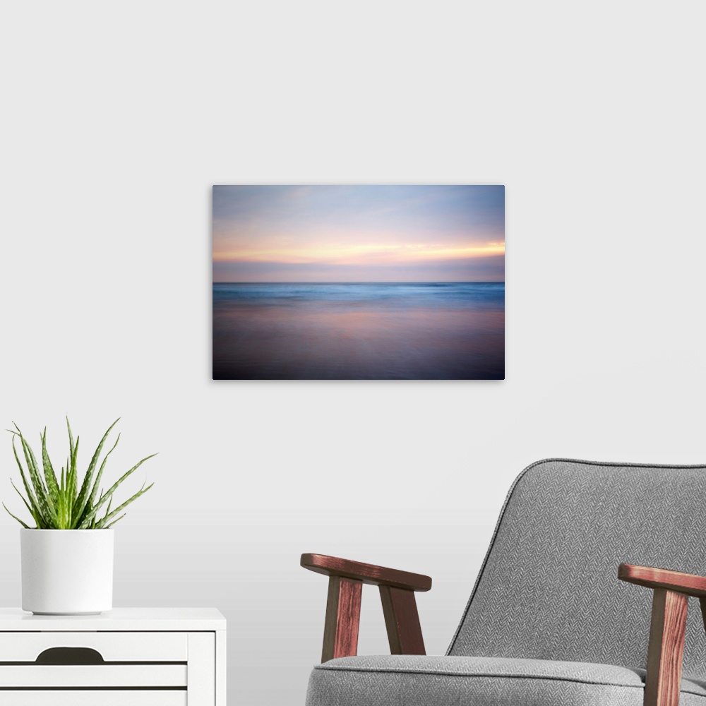 A modern room featuring An abstract fine art photograph of a sunrise that has a soft and blurred appearance.