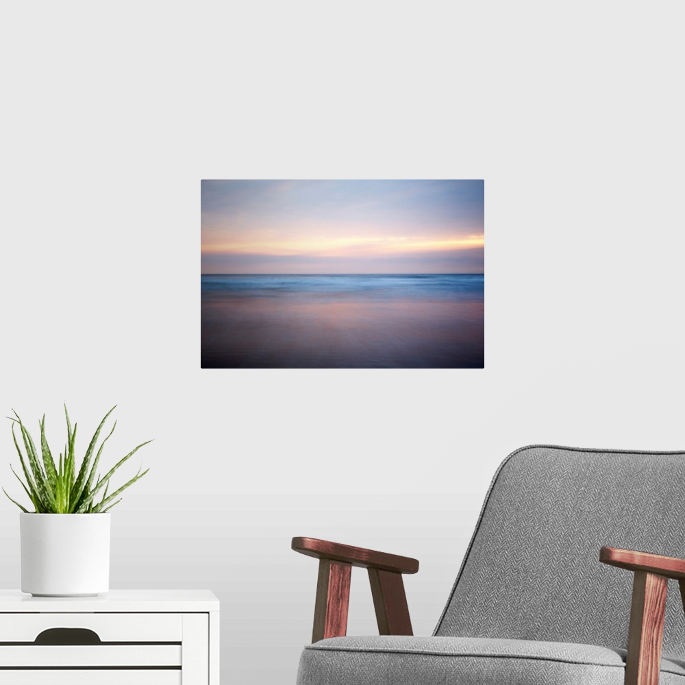 A modern room featuring An abstract fine art photograph of a sunrise that has a soft and blurred appearance.