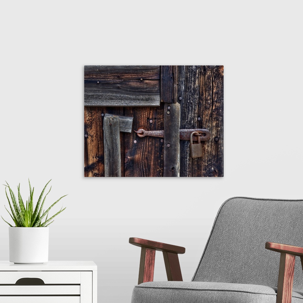 A modern room featuring Vintage metal lock on a wooden door full of nails.