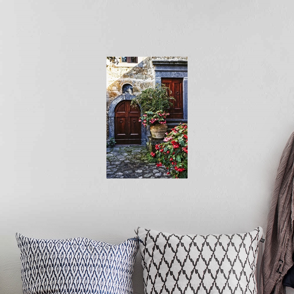 A bohemian room featuring Two wooden doors in a stone wall surrounded by blooming potted flowers.