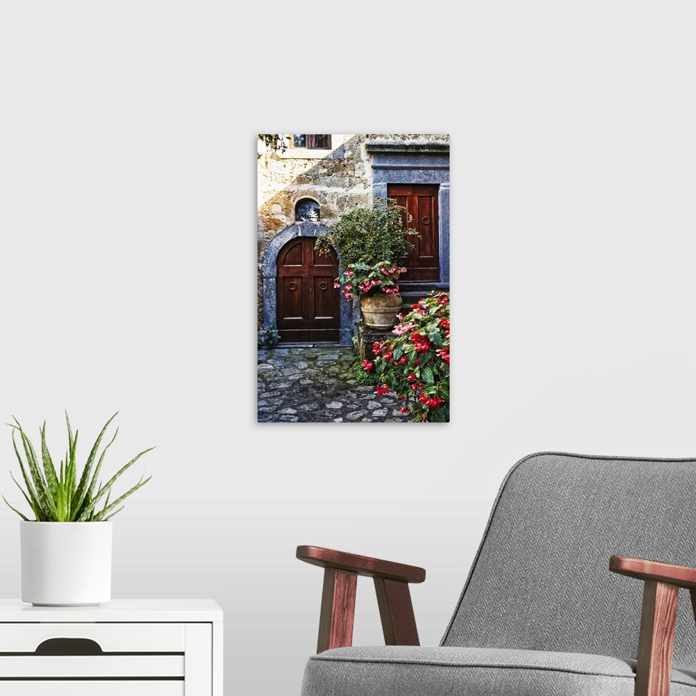 A modern room featuring Two wooden doors in a stone wall surrounded by blooming potted flowers.