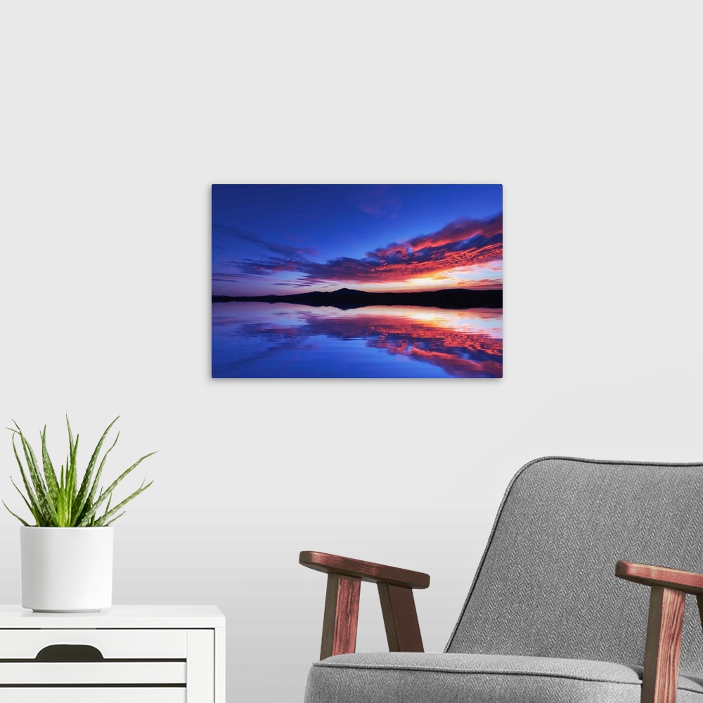 A modern room featuring Reflection of a sunset over the sea with mountains in the background
