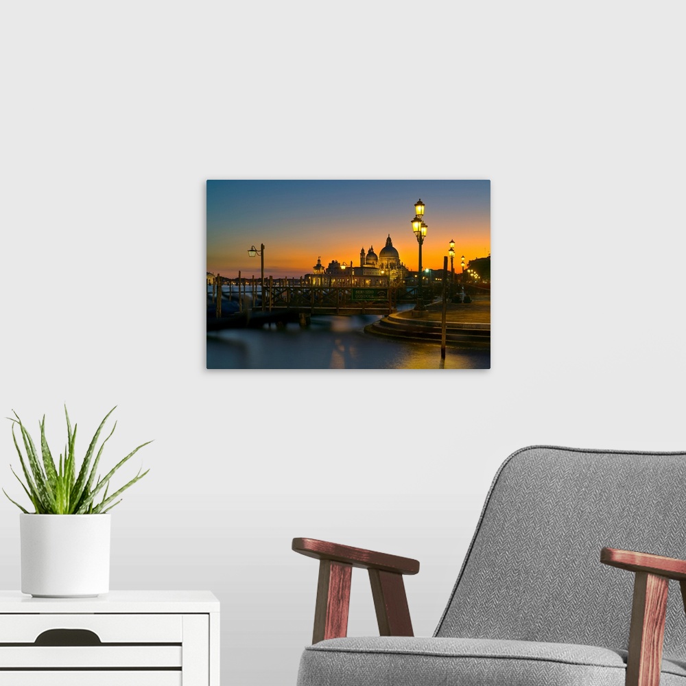 A modern room featuring Sunset over Venice, Italy with yellow lit lampposts and calm waters.