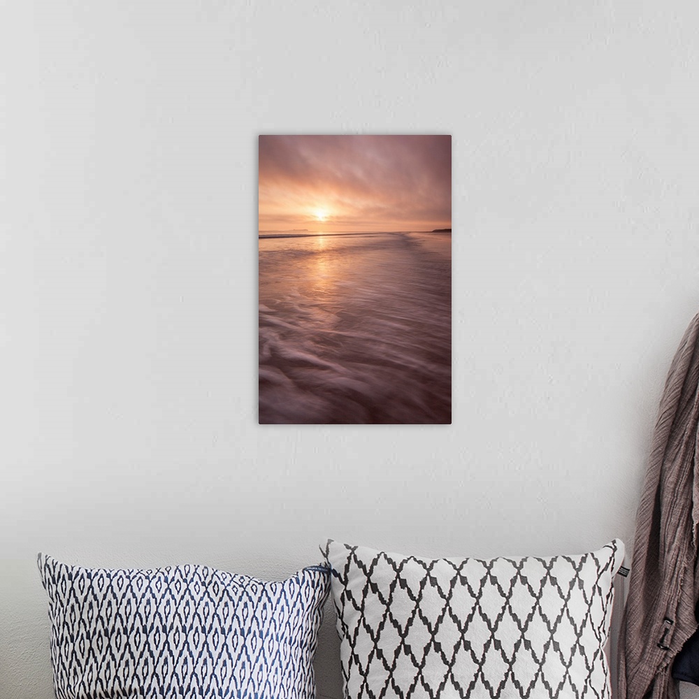 A bohemian room featuring A calm saescape at dawn with a glowing peach sky reflecting in the sea with swooshing waves.