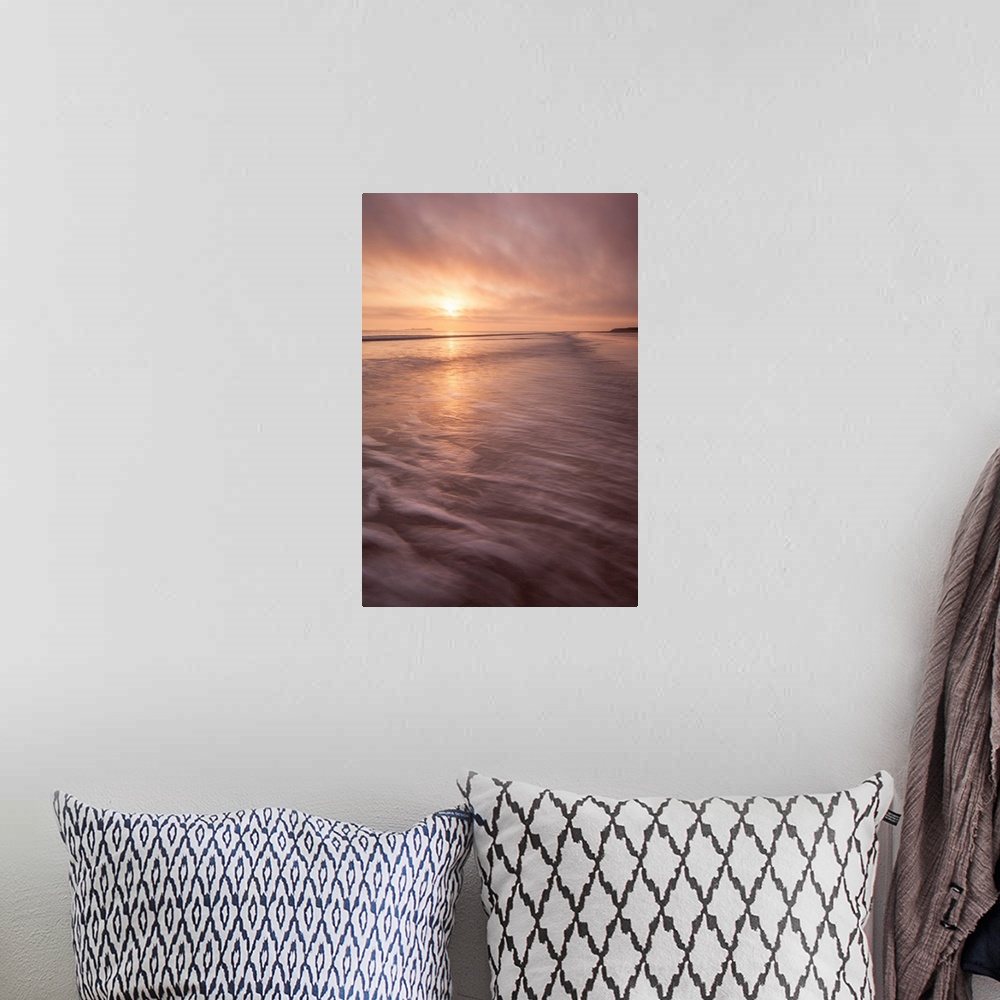 A bohemian room featuring A calm saescape at dawn with a glowing peach sky reflecting in the sea with swooshing waves.