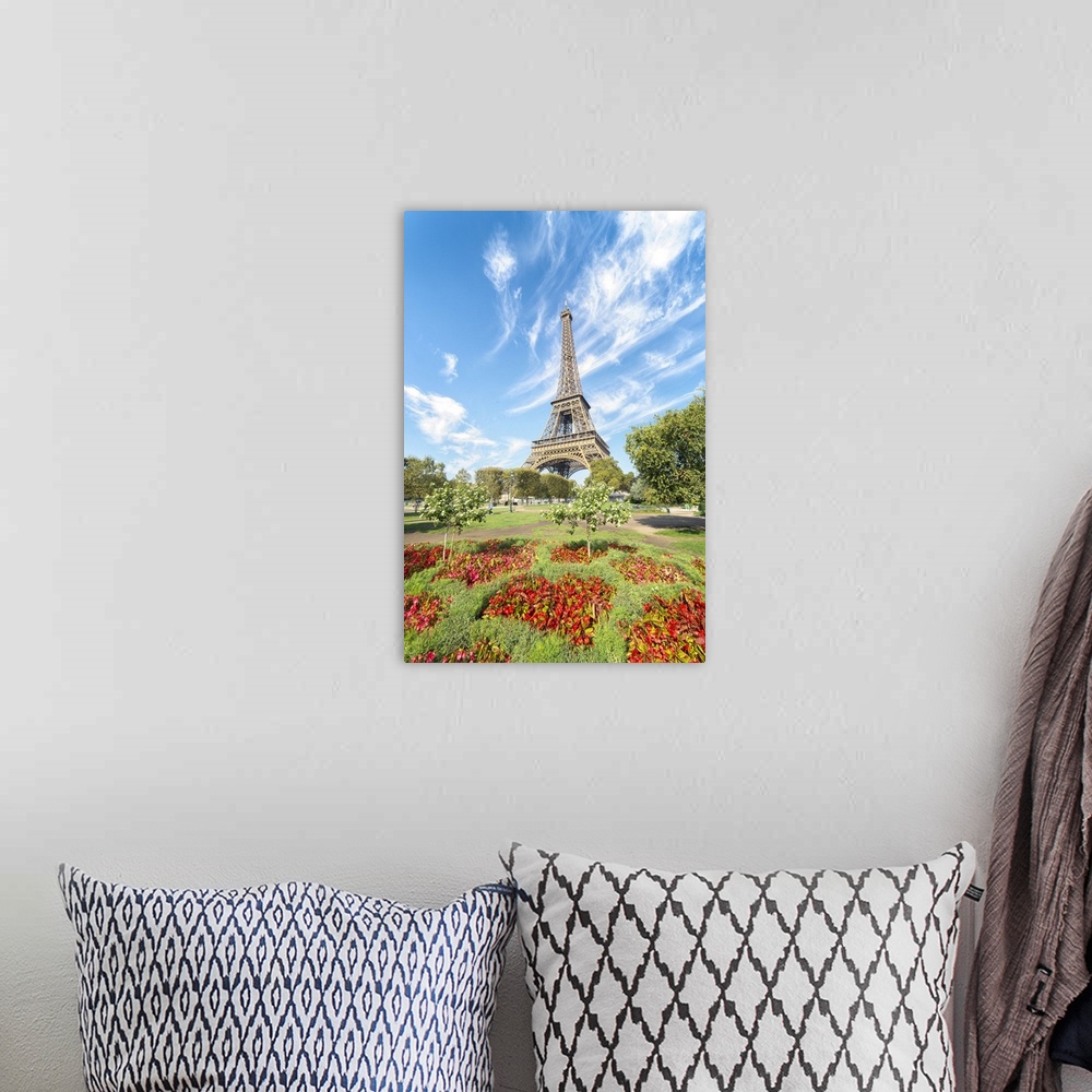 A bohemian room featuring Eiffel tower under a lignting blue sky in front of red flowers at summer.