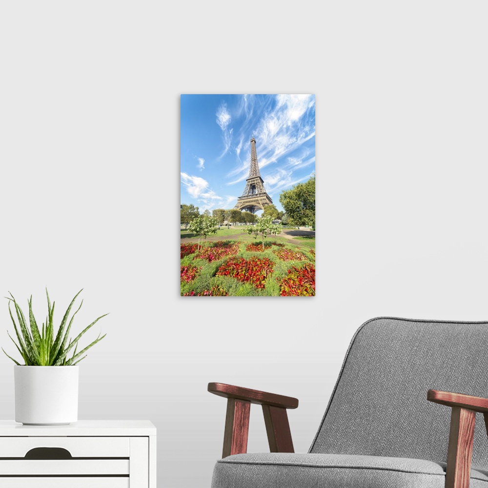 A modern room featuring Eiffel tower under a lignting blue sky in front of red flowers at summer.