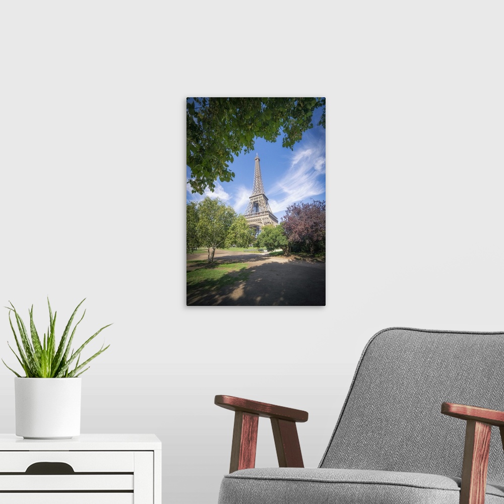 A modern room featuring Eiffel tower view from Champ de mars in Paris, France among trees and garden on summer under a bl...
