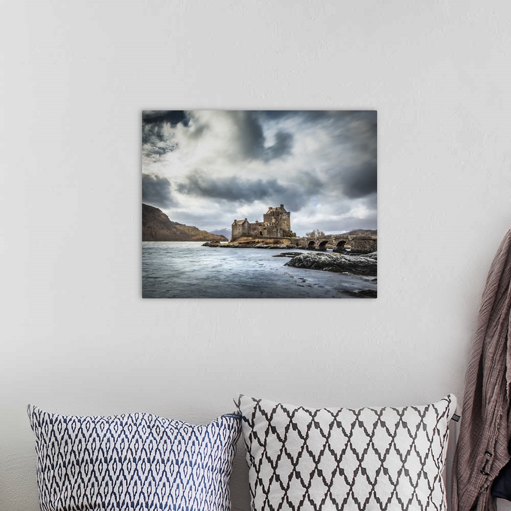 A bohemian room featuring Scottish Castle Eilean Donan with a moody grey sky and light blue waves with a bridge in the fore...