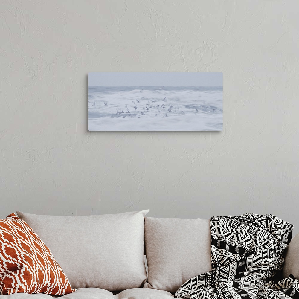 A bohemian room featuring Artistically blurred photo. Seagulls in search for food dive into the surf on a stormy day, witho...