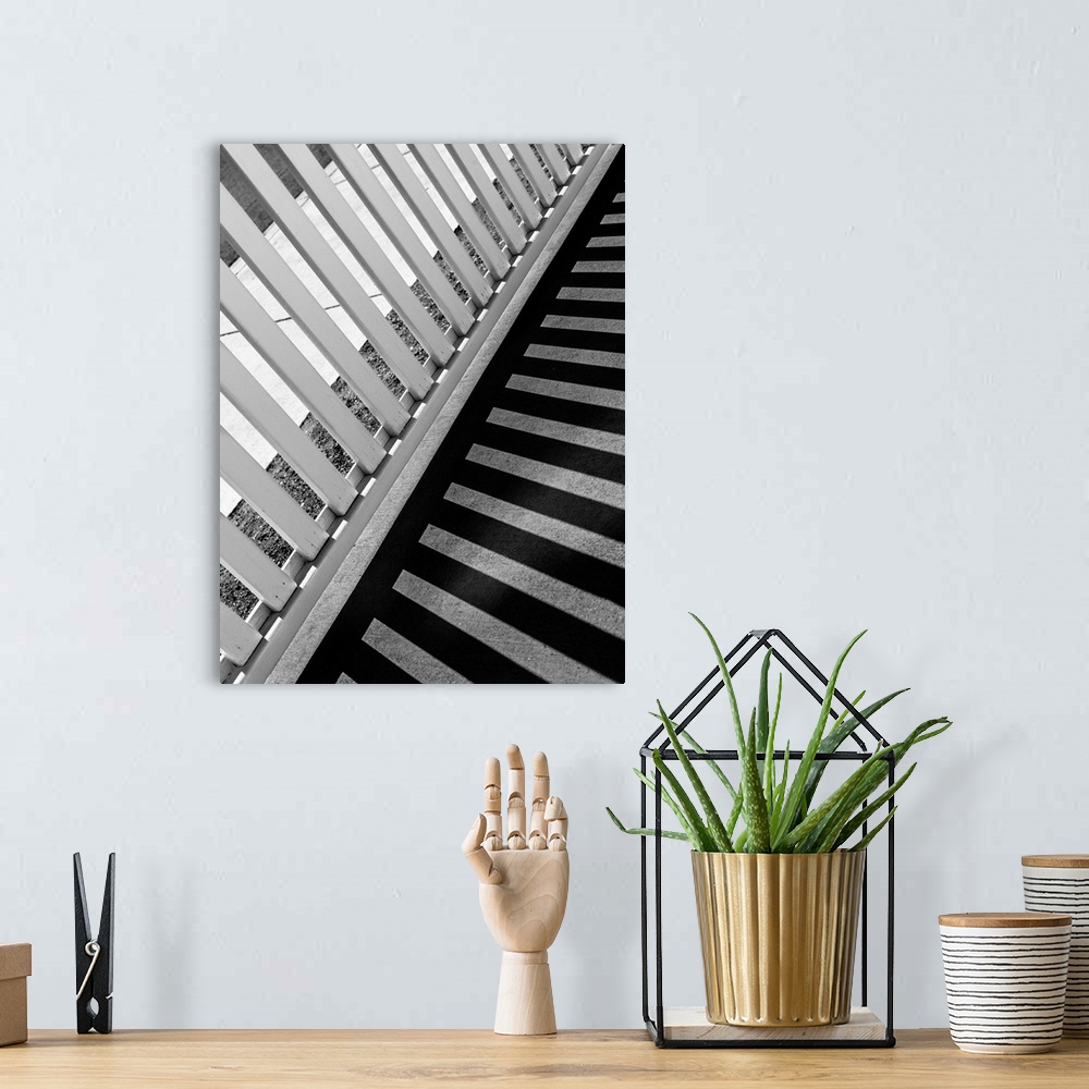 A bohemian room featuring Monotone image of a fence casting long striped shadows on a walkway.