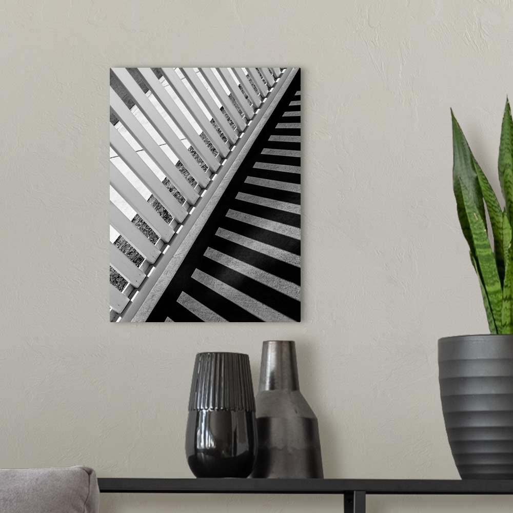 A modern room featuring Monotone image of a fence casting long striped shadows on a walkway.