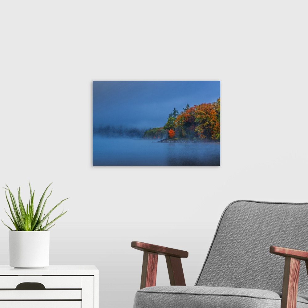 A modern room featuring Dense fog over a lake in the evening with autumn trees.