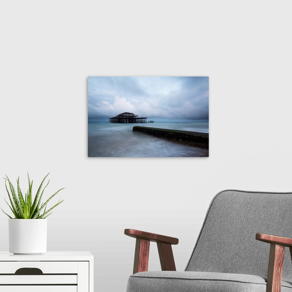 A modern room featuring A cool blue dramatic storm image of Brighton Pier, Sussex, UK with the Old Pier in stormy seas an...