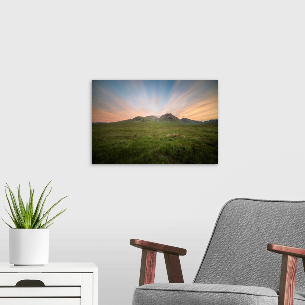A modern room featuring Glencoe valley at sunset next to etive mor in scotland, a green valley with mountains on background.