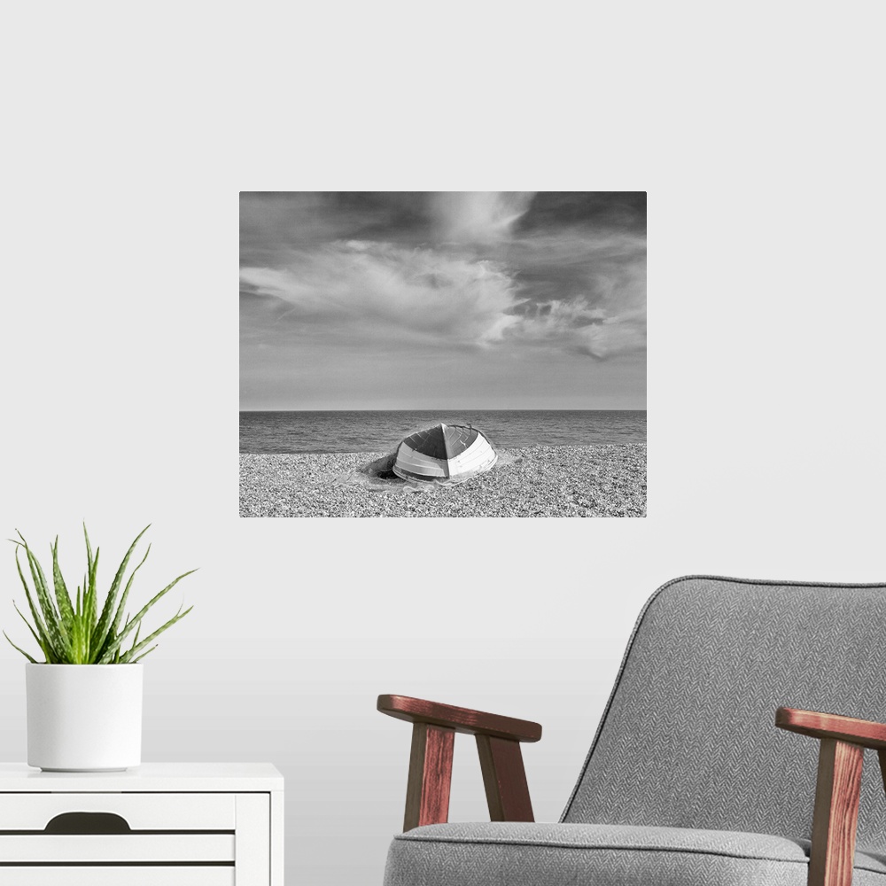 A modern room featuring A monochrome black and white image of an upturned rowing boat on an English shingle beach in brig...