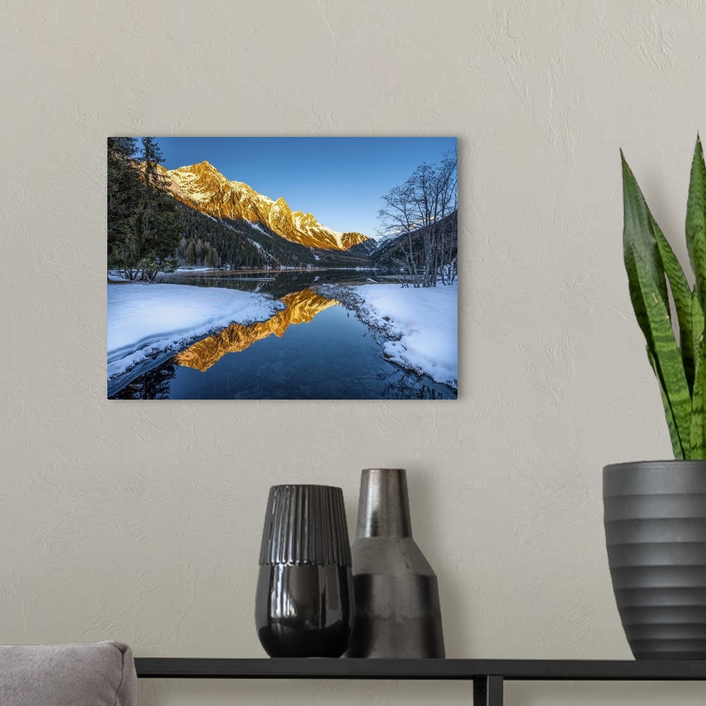 A modern room featuring An alpine landscape in the middle of Lake Anterselva after a heavy snowfall. The sunset with its ...