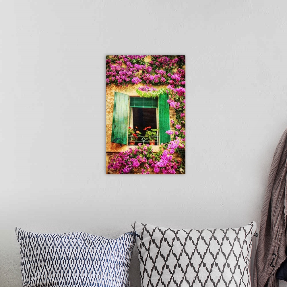 A bohemian room featuring Green shutters on a window surrounded by vibrant pink flowers growing on the wall.