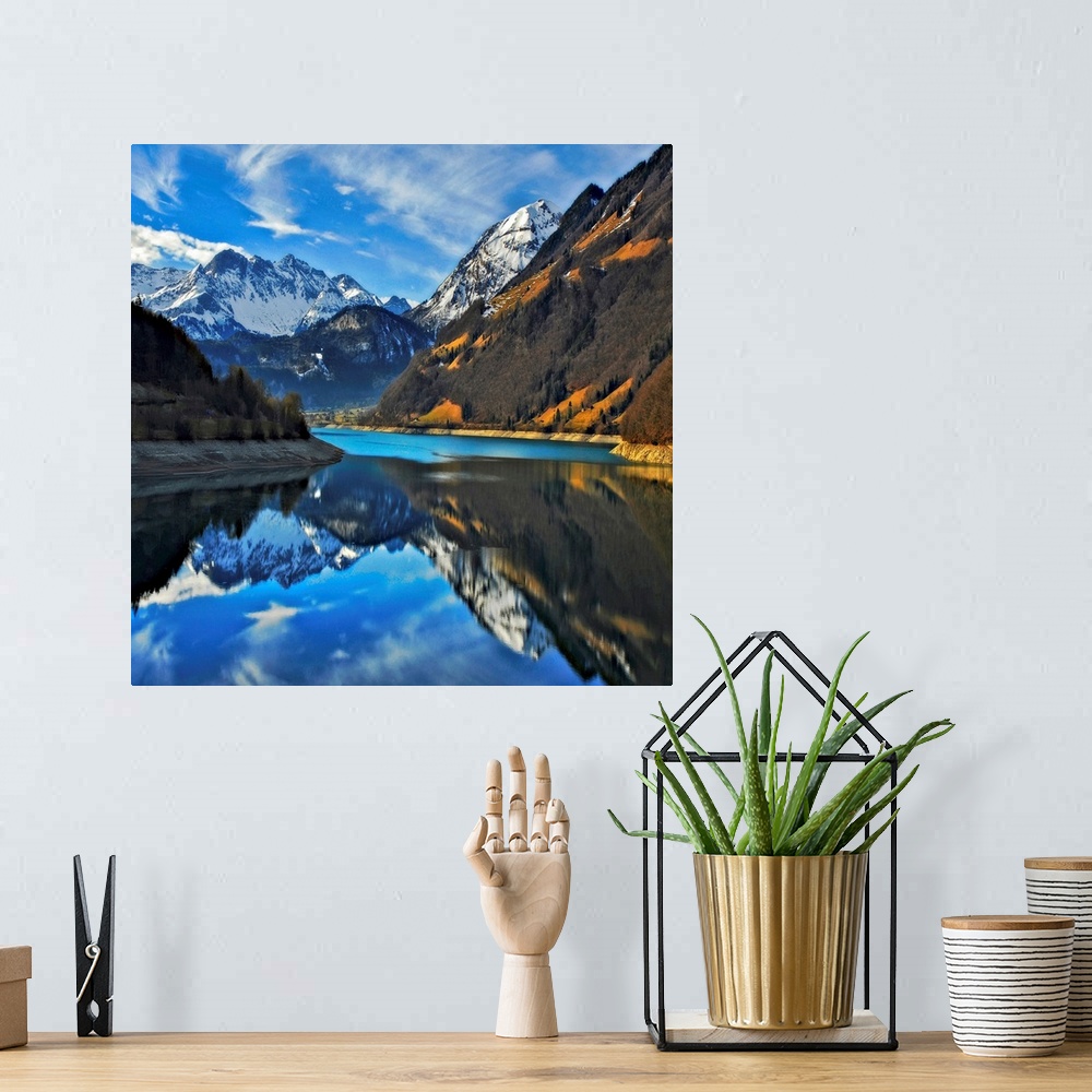A bohemian room featuring Square photograph on a big wall hanging of snow covered mountains beneath a blue sky, reflecting ...