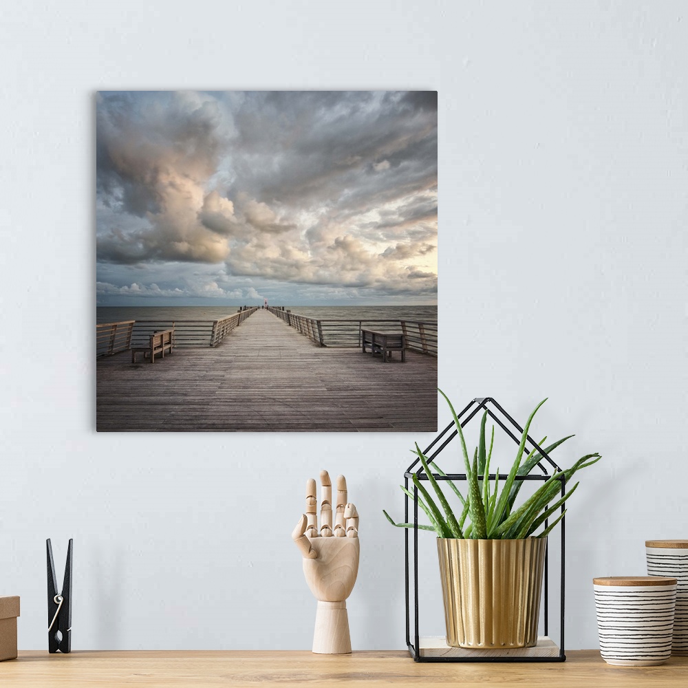 A bohemian room featuring A wooden pier leading to the ocean with dramatic clouds above.