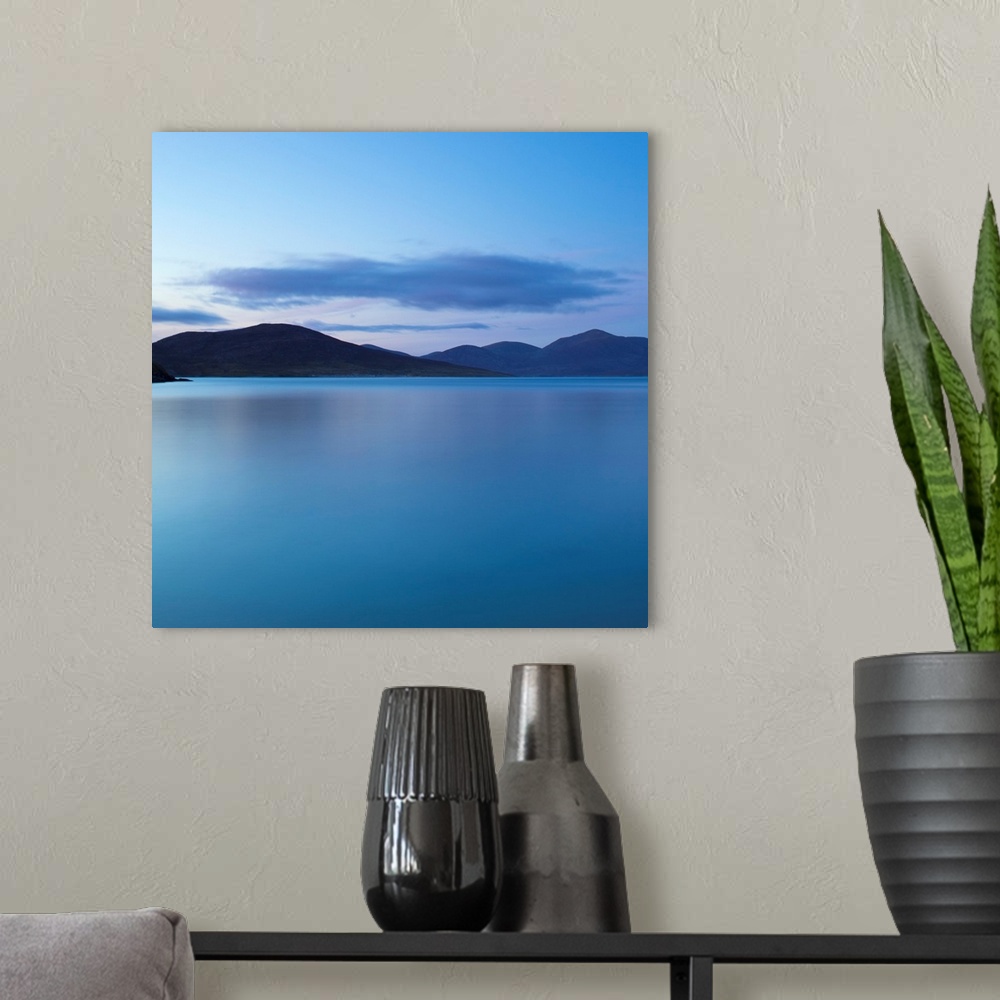 A modern room featuring A cool blue minimal zen-like seascape of flat calm water with silhouetted mountains.