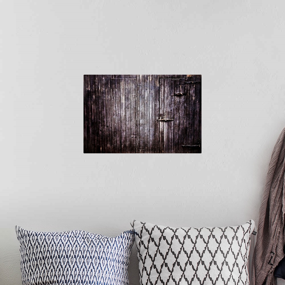 A bohemian room featuring Large photograph focuses on the side of an aged wooden building with a couple concealed entrances.