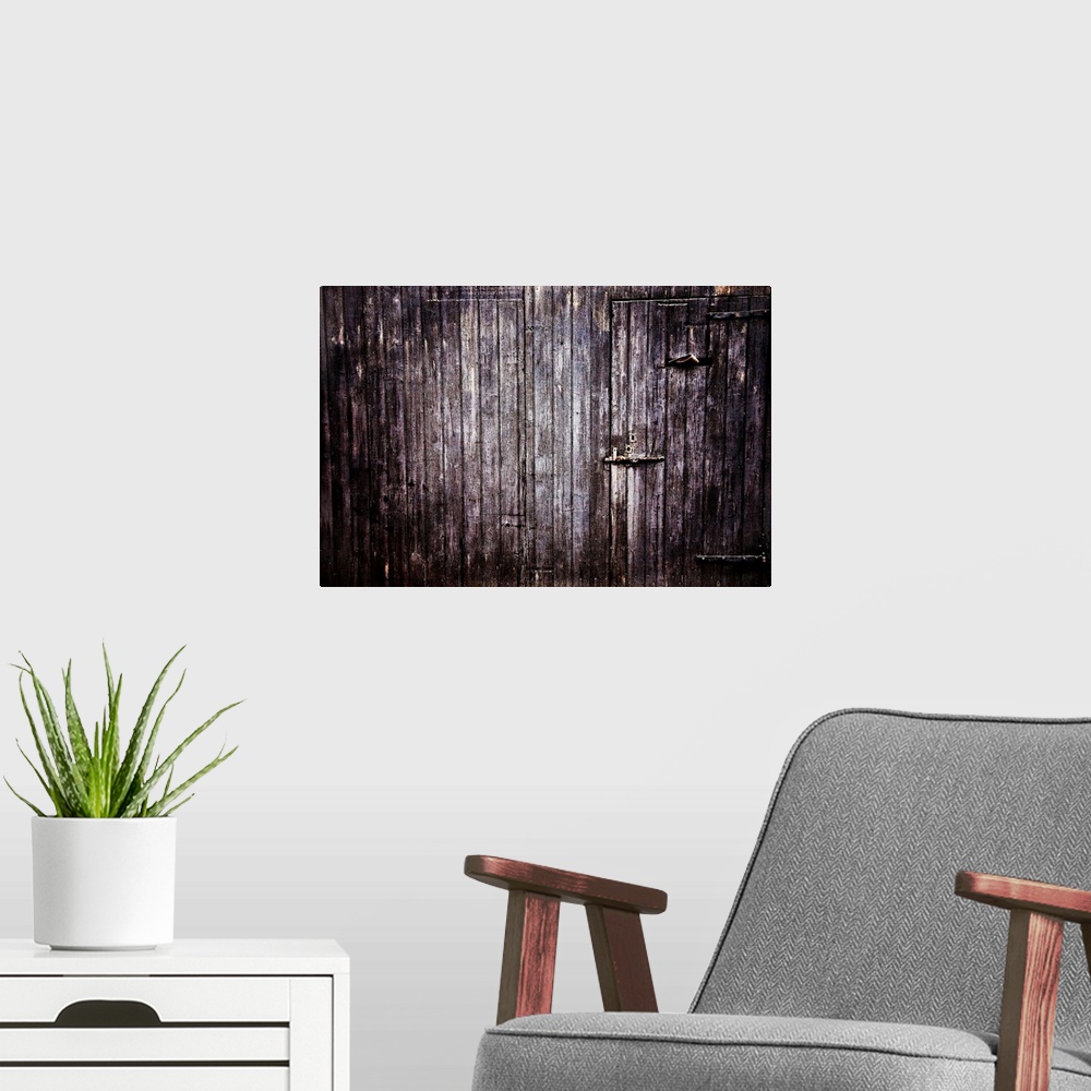 A modern room featuring Large photograph focuses on the side of an aged wooden building with a couple concealed entrances.