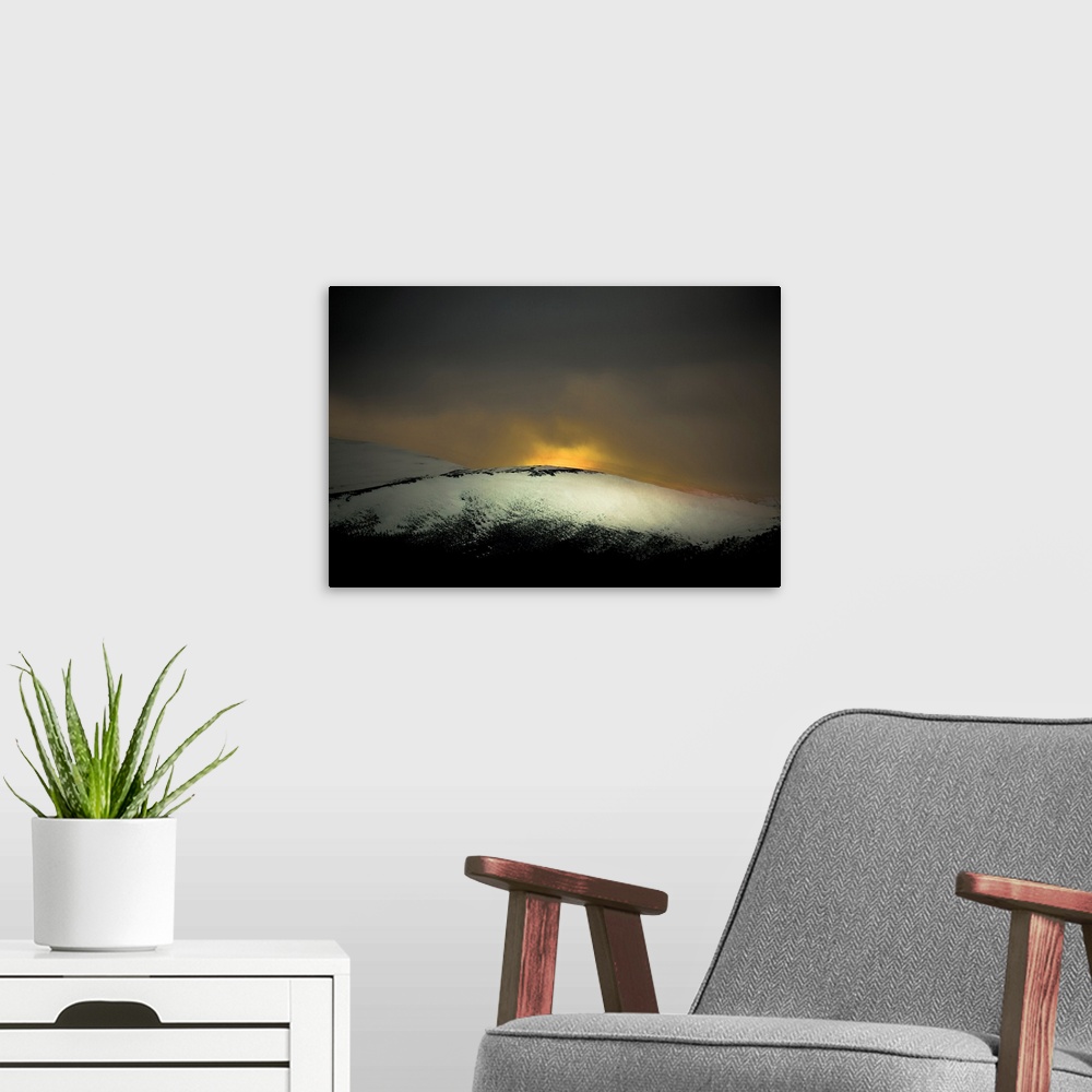 A modern room featuring A distressed photo a snow covered hill with dawn rising above it.