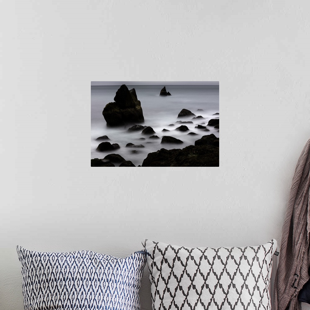 A bohemian room featuring Rocky outcroppings rising above the mist on the coast in Iceland.