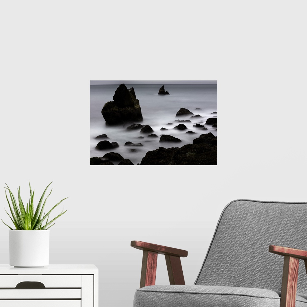 A modern room featuring Rocky outcroppings rising above the mist on the coast in Iceland.