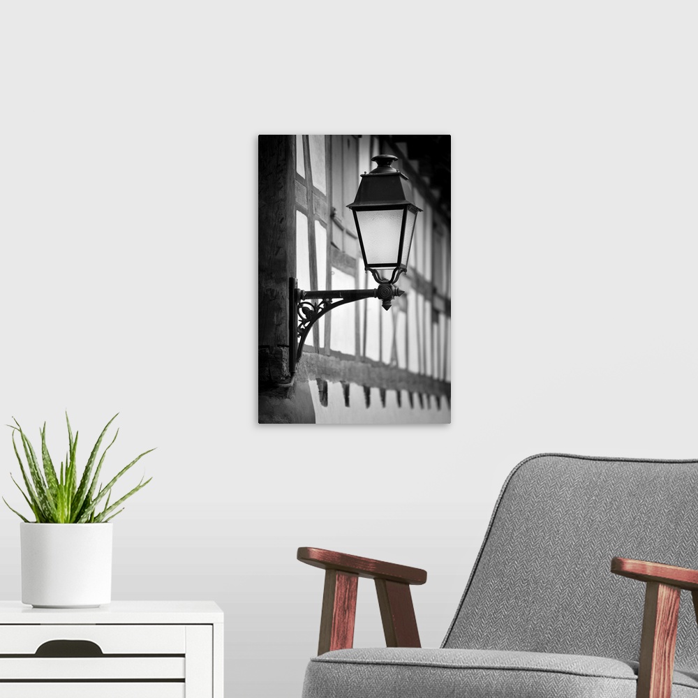 A modern room featuring A black and white photograph of a lantern hanging from the outside of a village building.