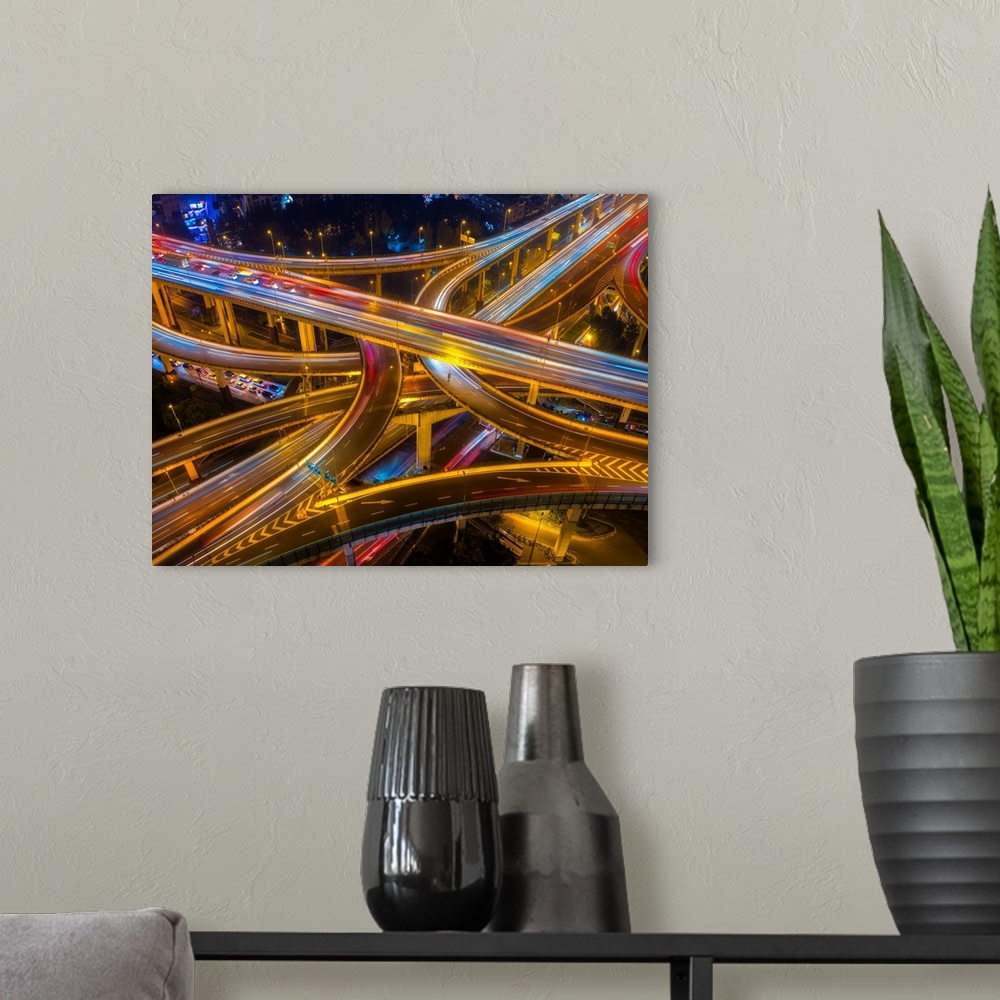 A modern room featuring Ariel view of highway bridges intertwining as cars drive by at night.