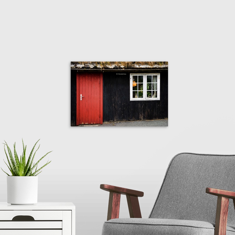A modern room featuring A black painted house with a bright red door and a white window.