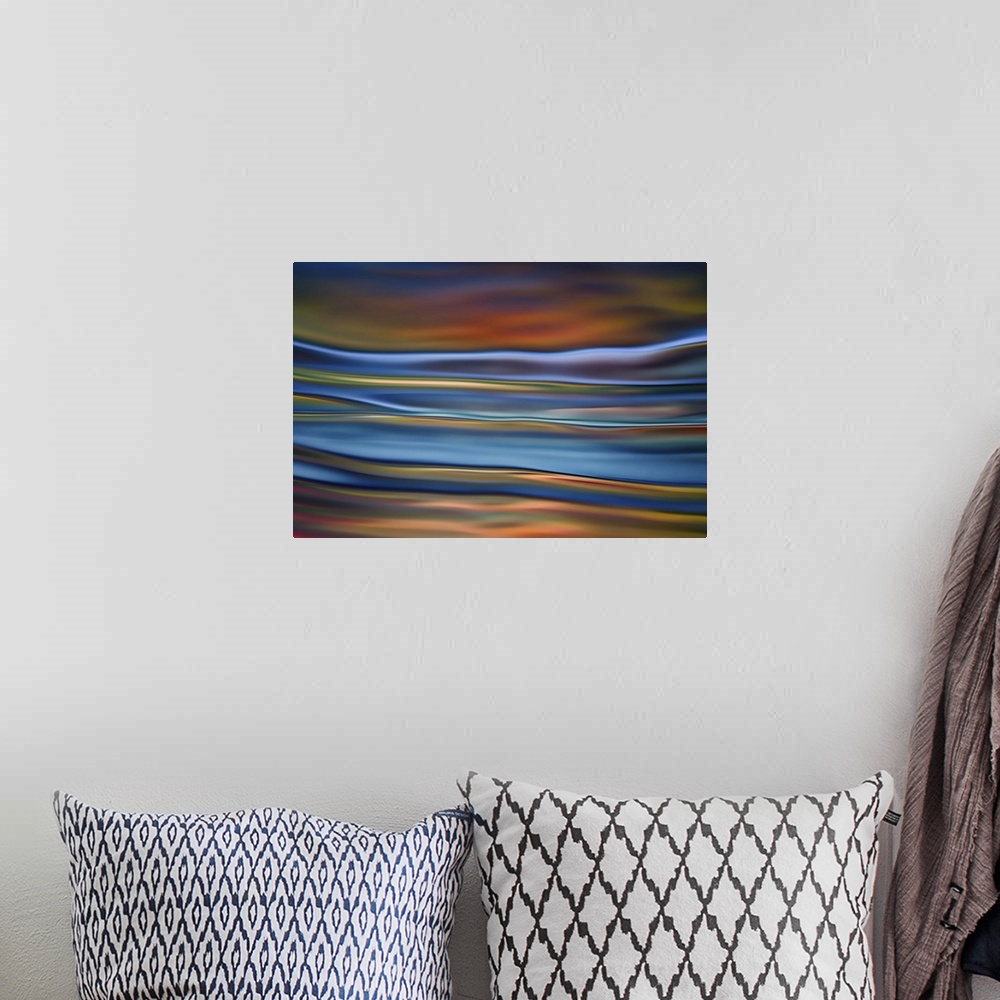 A bohemian room featuring Abstract photograph in orange and blue shades resembling ocean waves.