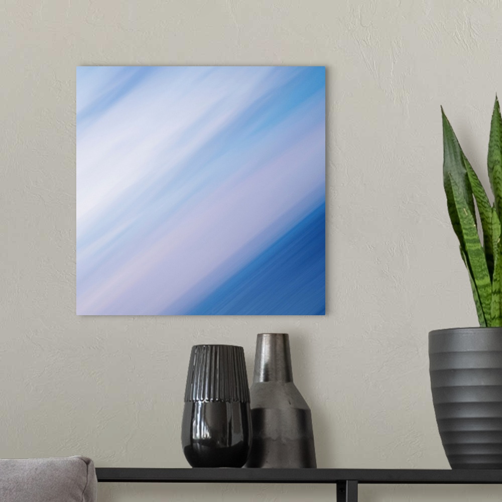 A modern room featuring A contemporary abstract of strong energetic diagonal lines in blues, whites and soft palest pinks...