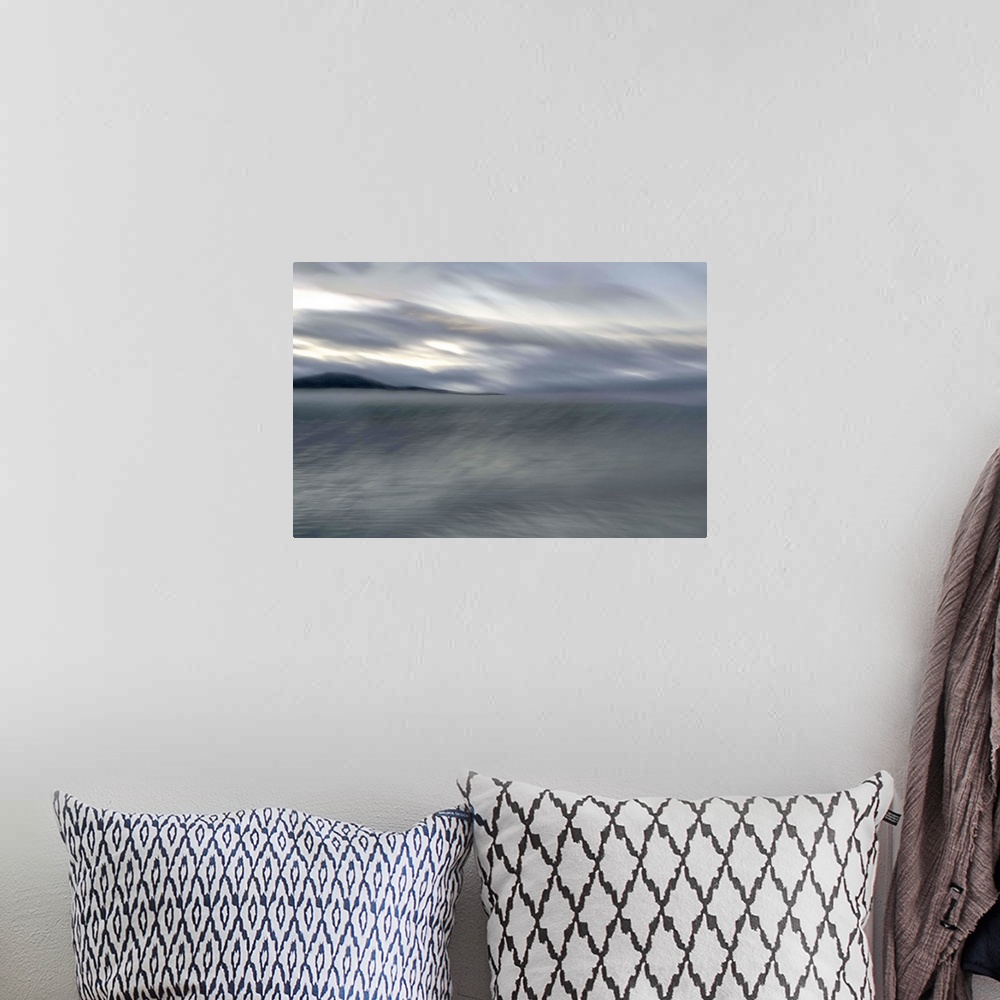 A bohemian room featuring Blurred image of a lake with stormy skies above and a mountain in the distance.