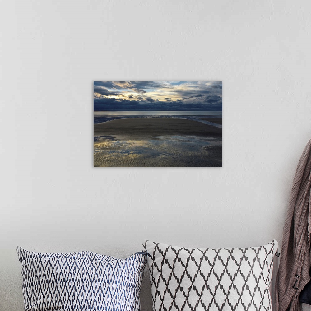 A bohemian room featuring Landscape photograph of an empty beach on a cloudy day with the sky reflecting onto the puddles i...